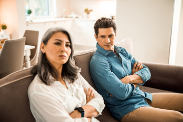 Mature couple sitting on couch while having quarrel