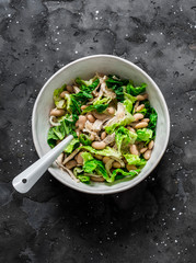 Warm salad with beans, baked chicken breast, romaine lettuce on a dark background, top view