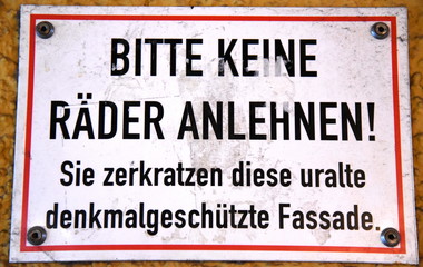 Schild an einer denkmalgesch&uuml;tzten Fassade: "Bitte keine R&auml;der anlehnen!"