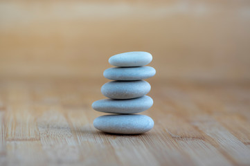 Fototapeta na wymiar Stone cairn on wooden background, five stones tower, simple poise stones, simplicity harmony and balance, rock zen