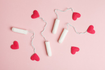women's health care, cotton tampons with red hearts as blood drops on rose background, female...