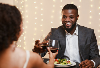 Happy afro man in suit toasting with his girlfriend