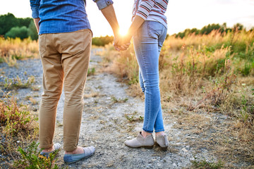 Close up of couple standing outdoors in nature and holding hands during sunset