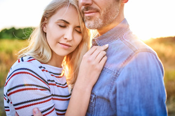 Fototapeta premium Close up of cute couple embracing while standing outdoors during sunset