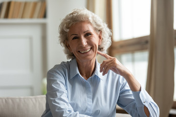 Portrait of smiling old woman relaxing on sofa at home.