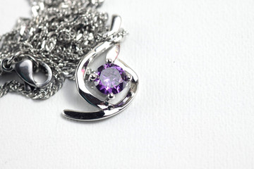 Close up shot of white golden pendat with shiny purple stone