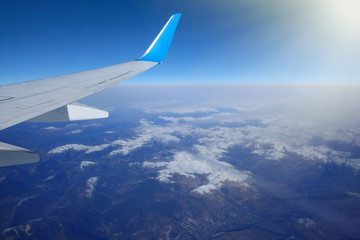 Fototapeta na wymiar View of the wing of an airplane over the snowy mountains. Beautiful landscape.