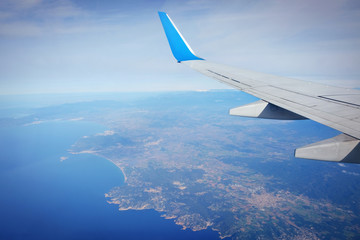 Fototapeta na wymiar Window view of travel tourism airplane. The wing of an airplane flying over the sea.