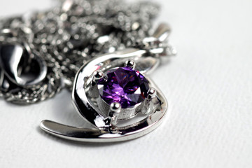 Close up shot of white golden pendat with shiny purple stone