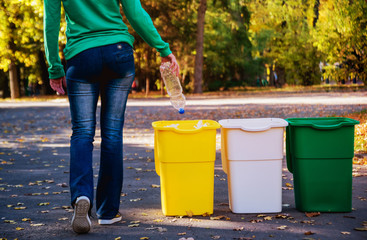 Volunteer girl sorts garbage in the street of the park. Concept of recycling. 