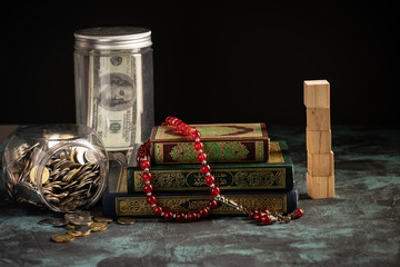 Zakat concept: Quran and tasbih with jar full of coins