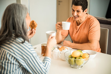 Happy man is holding cup of tea at home