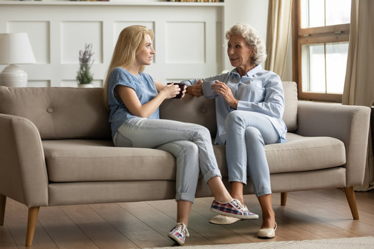 Smiling middle aged mother chatting with grown up daughter.
