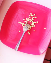 pills in a red plate with a fork