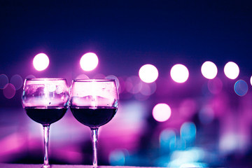 Two glasses of wine on a night city lights background. Blue shades.