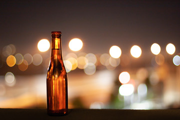 A full bottle of beer on a night city lights background