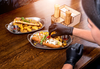 Two hungry young men eating a hot dogs in cafe. Restaurant