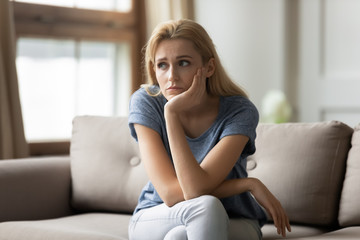 Stressed upset young blonde woman thinking of personal troubles.