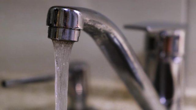 Water flows down from the kitchen faucet. Concept. Clean water flowing from a chrome tap in the kitchen.