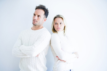 Young beautiful couple wearing casual t-shirt standing over isolated white background skeptic and...
