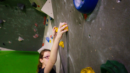 girl bouldering on rocks and grips