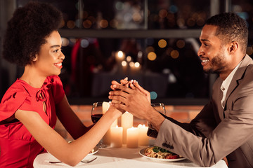 Loving Boyfriend And Girlfriend Holding Hands Sitting In Restaurant