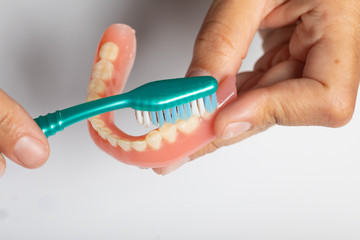Fototapeta na wymiar Cleaning dental prothesis with toothbrush