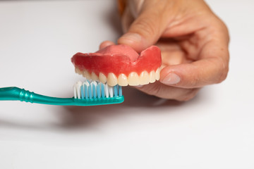 Fototapeta na wymiar Oran hygiene: Cleaning dental prothesis with toothbrush