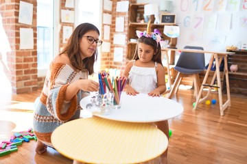 Beautiful teacher and toddler wearing unicorn diadem around lots of toys at kindergarten