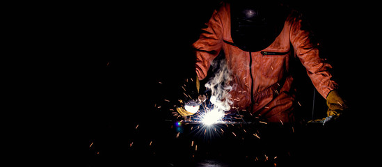 A man wearing safety mask and suit is welding metal