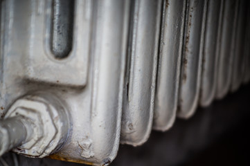 Close-up of a cast-iron old radiator for a heating system of a house and living quarters painted white