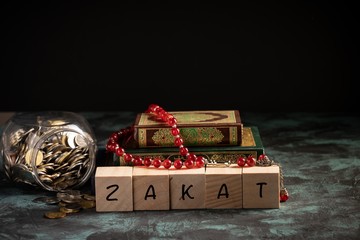 Zakat concept: Quran and tasbih with jar full of coins. The wordings on the book is arabic words which means Holy Quran