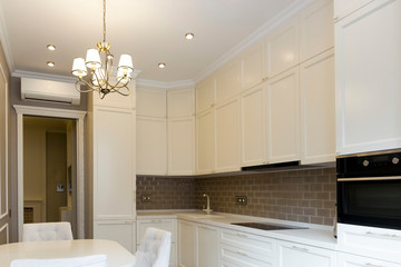 Facade of a white, wooden kitchen with a brown apron in brick. Scandinavian style kitchen design