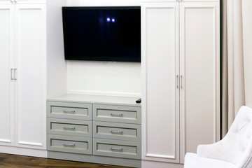 A television between two white cabinets. Laconic interior design