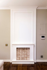 Decorative fireplace on the wall - modern interior. White frame and red brick