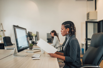 Mixed race business woman working with documents in coworking office.