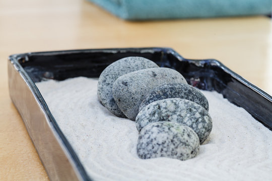 small zen decoration with sand and granite stones that calm and are staggered. In the background a lime green towel