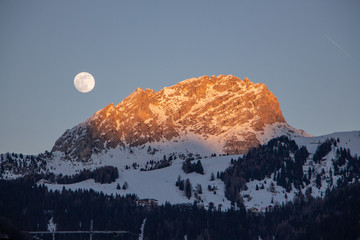 Moon rise and sunset over Italy dolomites with gorgeous light and snowy mountains val di fassa