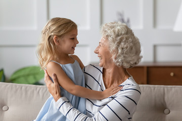 Obraz premium Happy middle aged grandmother holding on lap cute small granddaughter.