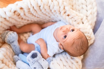 Adorable baby lying down over blanket on the floor at home. Newborn relaxing and resting...