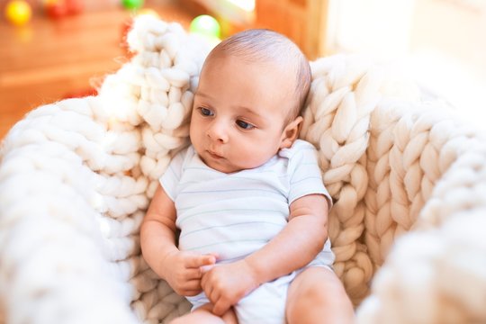 Adorable baby lying down over blanket on the floor at home. Newborn relaxing and resting comfortable