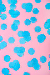 Blue confetti on pink background. Flat lay, top view.