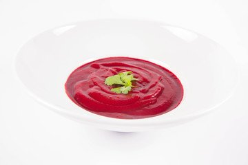 Beetroot cream soup decorated with coriander leaf	
