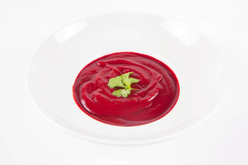 Beetroot cream soup decorated with coriander leaf	