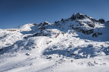 Fototapeta na wymiar Hiker alone in winter mountain, in front of high peaks