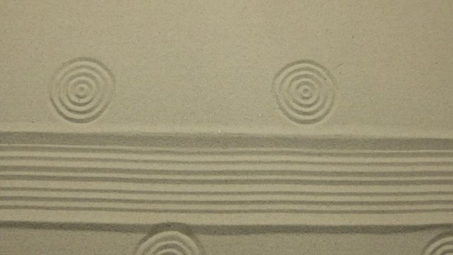 Simple spiritual patterns in a japanese zen garden with concentric circles and parallel lines. Zoom.