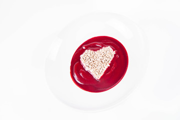 Beetroot cream soup decorated with a heart made of yoghurt and sunflower seeds