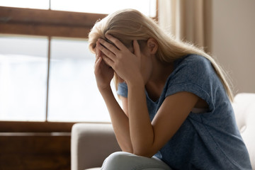 Stressed young blonde woman suffering from head ache.