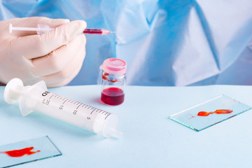 Woman working with blood sample in laboratory, closeup on blue background