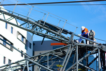 Melbourne, Australia - May 2 2018 - The worker adjusts the fasteners on the construction mobile crane on the sky background